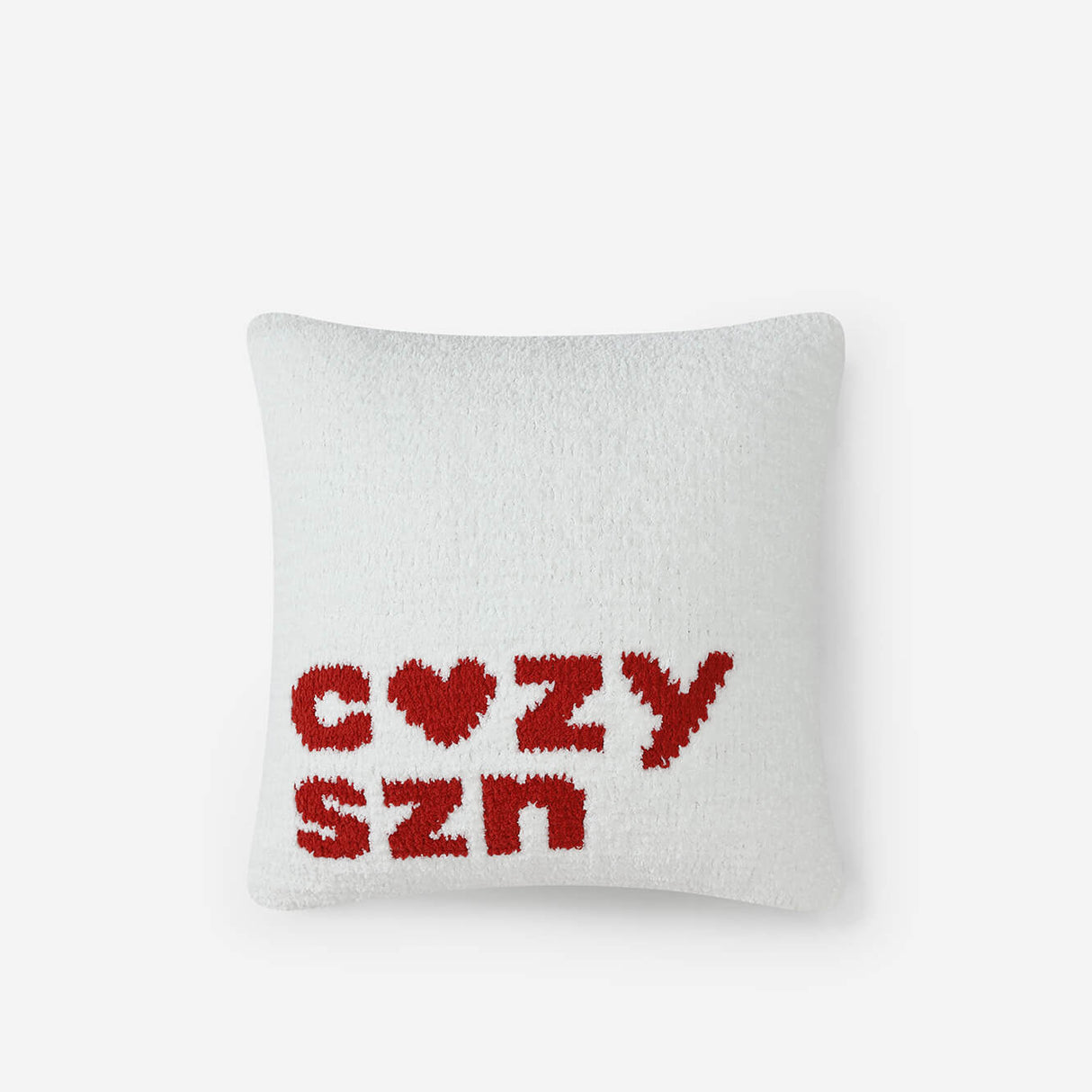 White pillow with red text 'COZY SZN' on a white background