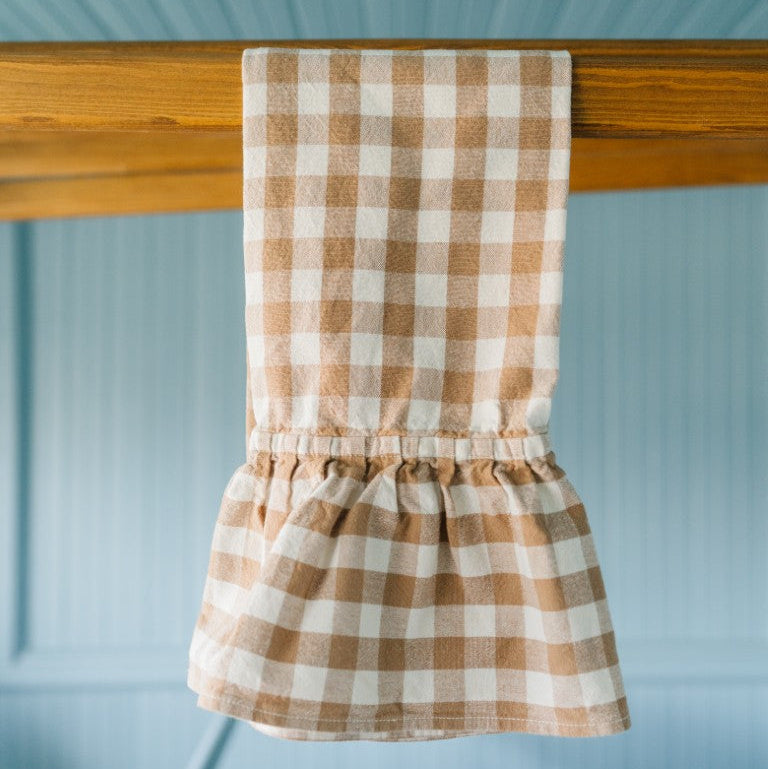 Brown and white checkered towel hanging on a wooden rod against a light blue wall.