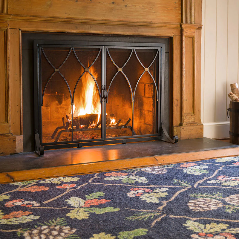 Fireplace with lit fire and decorative screen, floral-patterned carpet in foreground