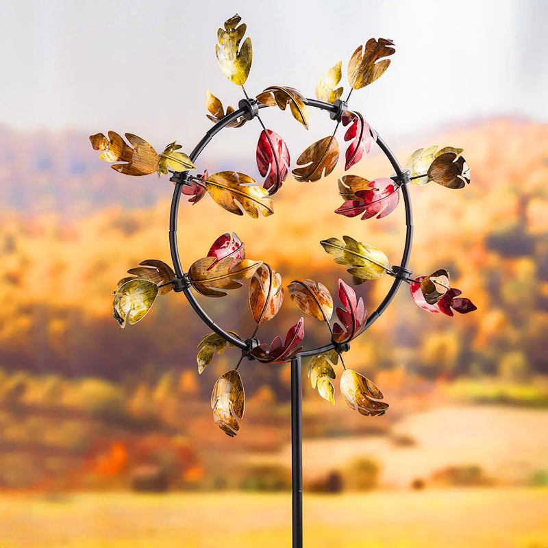 Decorative wind spinner with colorful leaves against a blurred autumn landscape