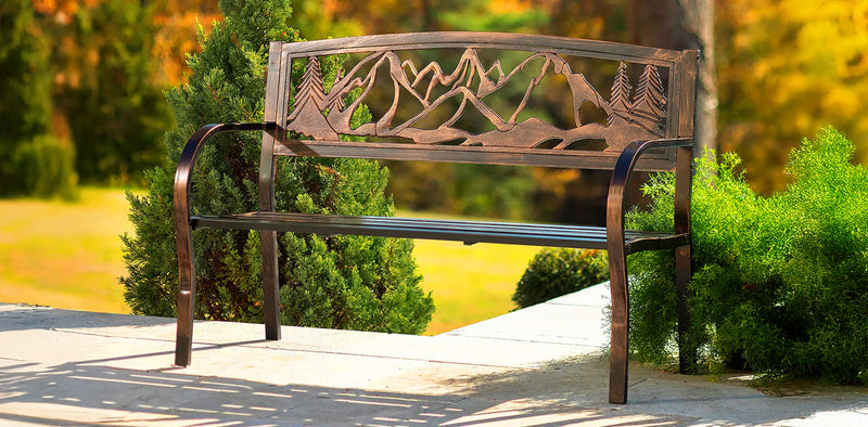 Decorative metal bench with mountain design in a garden setting