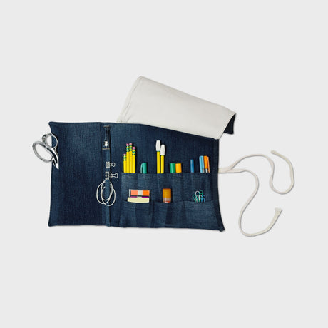 Denim pouch with various tools and supplies on a white background