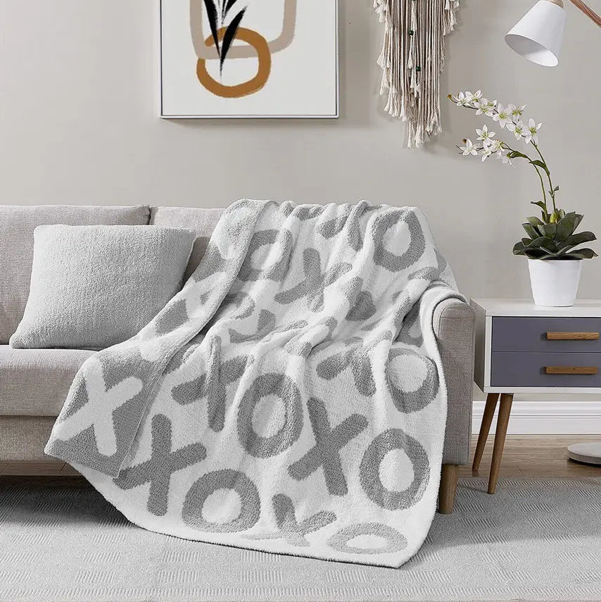 Gray patterned blanket draped over a gray sofa in a living room setting.