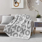 Gray patterned blanket draped over a gray sofa in a living room setting.