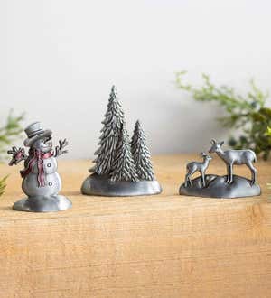 Pewter keepsake decorations of a snowman, deer and christmas tree on a mantel. Shop Gifts Under $30